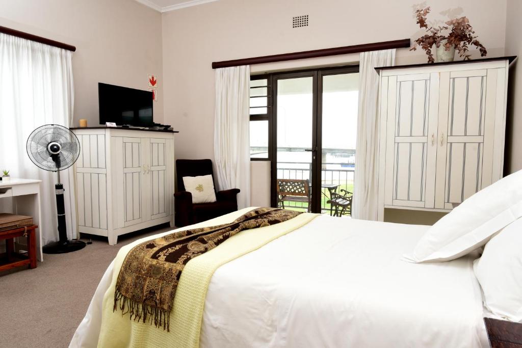a bedroom with a white bed and a balcony at Riviera Hotel & Chalets in Velddrif