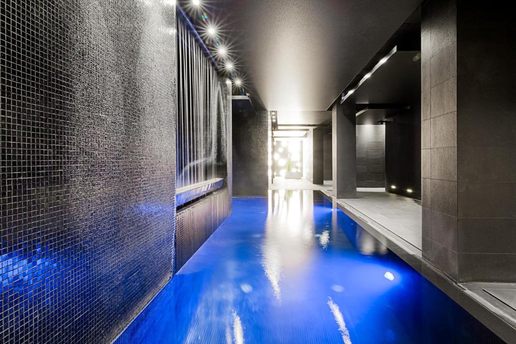 a swimming pool with blue water in a bathroom at M Hotel in Łódź