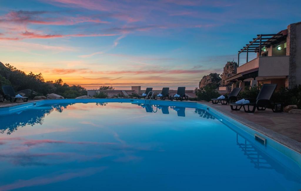 a large swimming pool with a sunset in the background at Gravina Resort & Apartments in Costa Paradiso