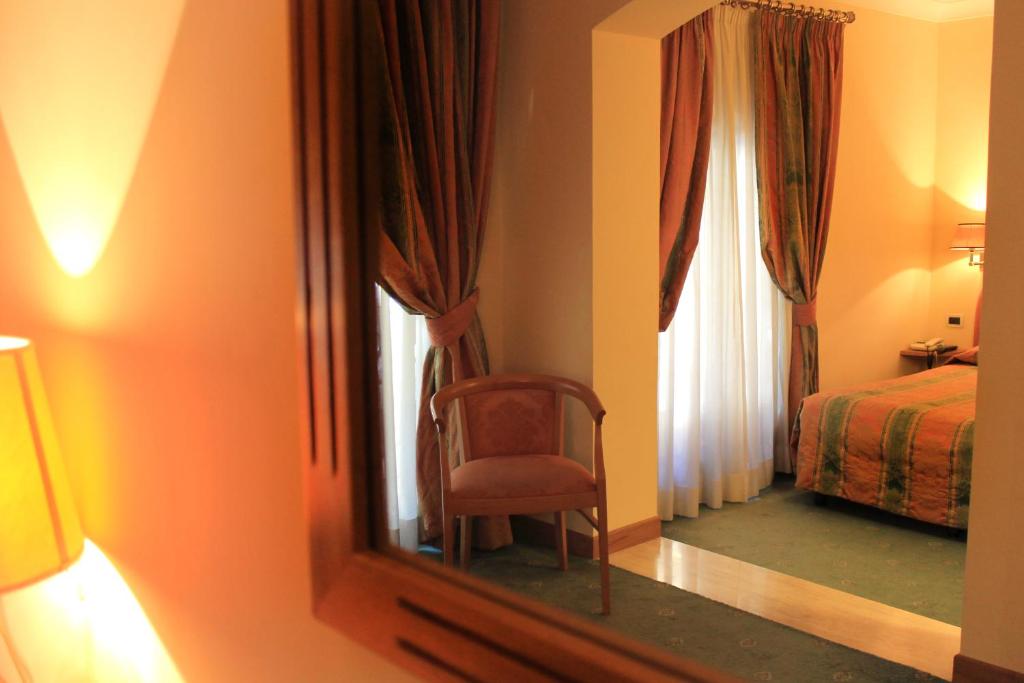 a mirror in a room with a chair and a bed at Hotel Villa Delle Rose in Rome