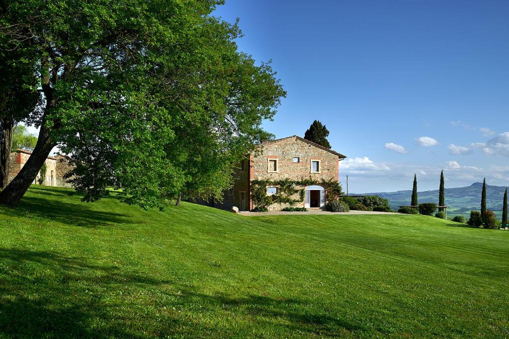 an old house on a grassy hill with a tree at B&B Palazzolo La Foce in Chianciano Terme