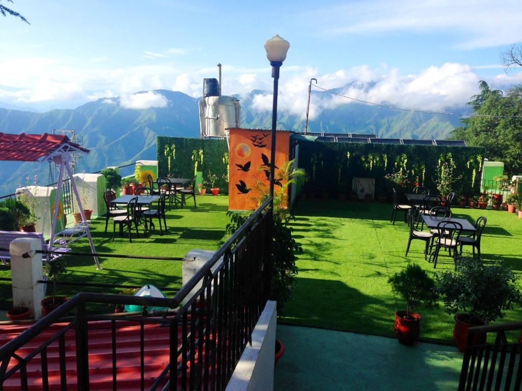 a patio with tables and chairs and mountains in the background at Hotel SunGrace in Mussoorie