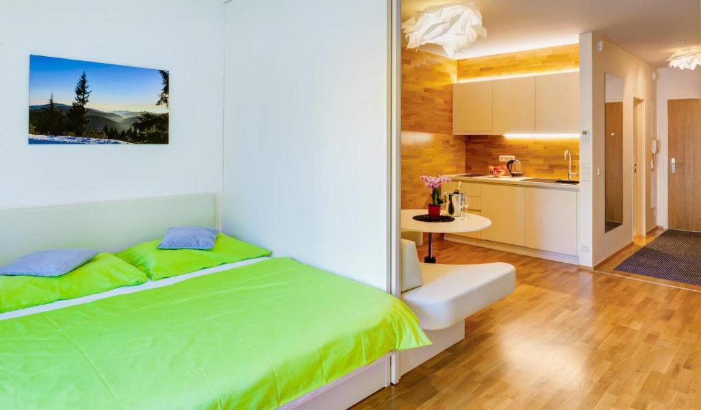 a bedroom with a green bed and a kitchen at Apartman Medvědín 306 in Špindlerův Mlýn