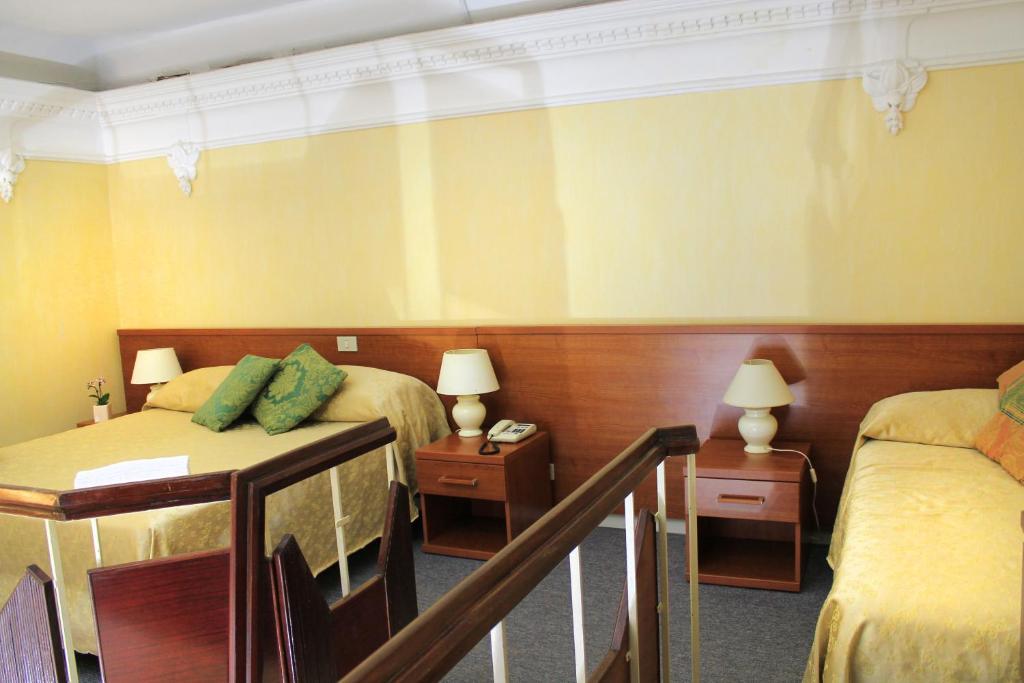 a hotel room with two beds and two tables at Hotel Villa Delle Rose in Rome