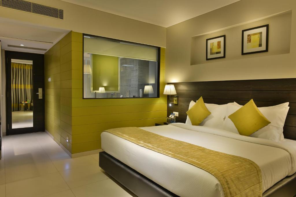a bedroom with a large bed with yellow walls at The Fern Residency, Vadodara in Vadodara