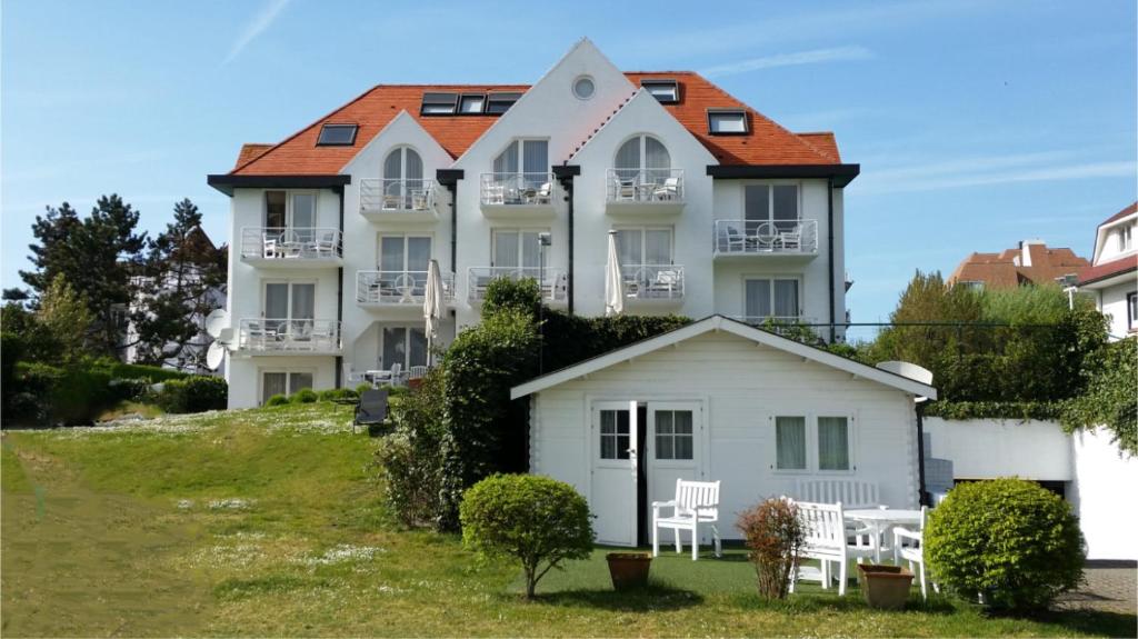 een groot wit gebouw met een rood dak bij Hotel Approach in Knokke-Heist