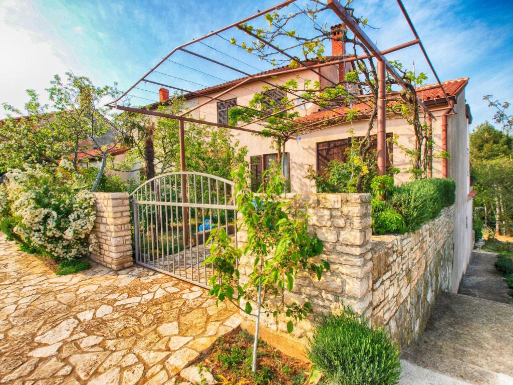 a house with a gate and a stone wall at Apartments Dvorine 1210 in Banjole