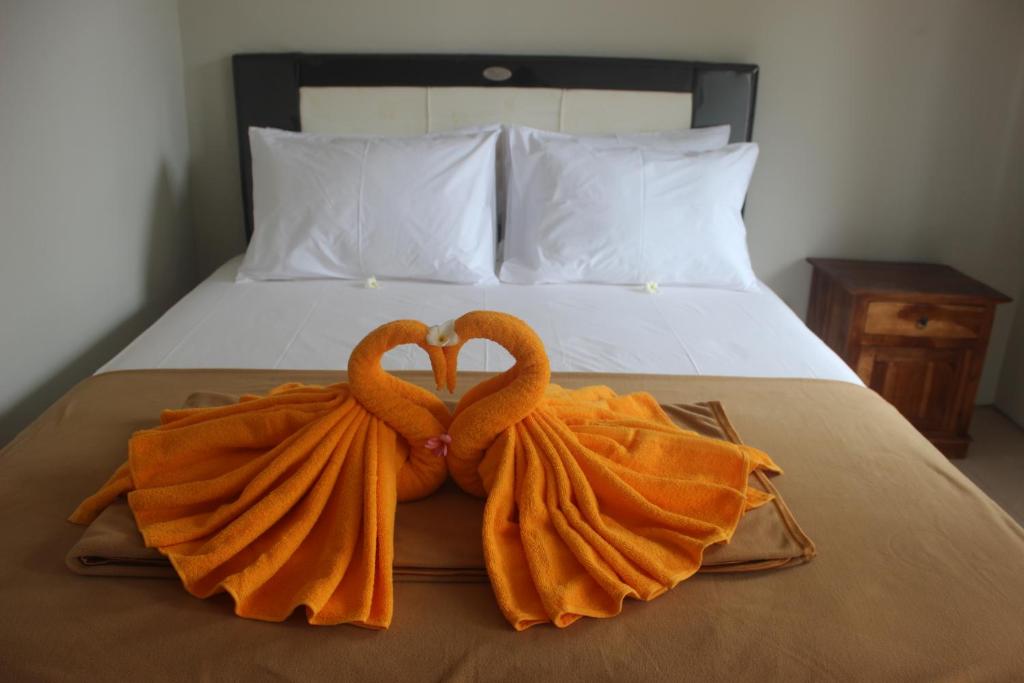 dos toallas en forma de corazones en una cama en Adi Bali Homestay, en Uluwatu