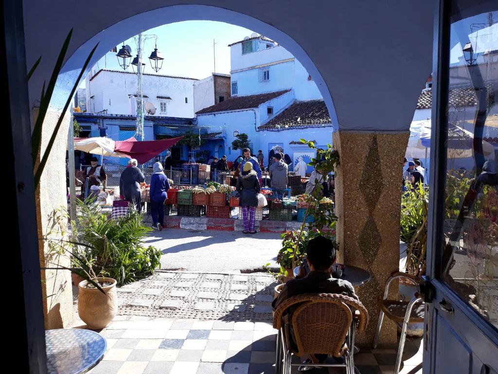 Ein Mann, der auf einem Markt im Freien auf einem Stuhl sitzt. in der Unterkunft Hotel Asmara in Chefchaouen