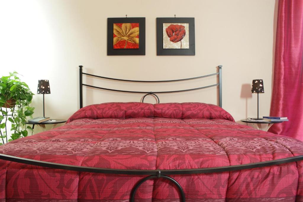 a bedroom with a red bed with two pictures on the wall at Vesuvio Bed & Breakfast in Scafati