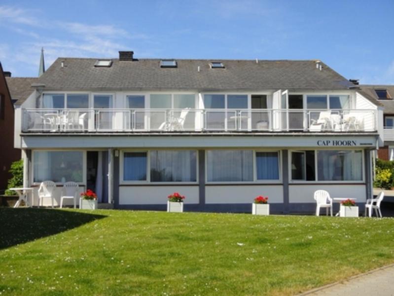 a large white house with chairs on a lawn at Gaestehaus Cap Hoorn in Helgoland