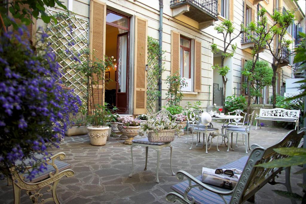 un patio con mesa, sillas y plantas en Antica Locanda Leonardo, en Milán