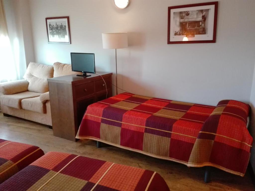 een hotelkamer met een bed en een bank bij Hostal Patrón in Castañares de Rioja