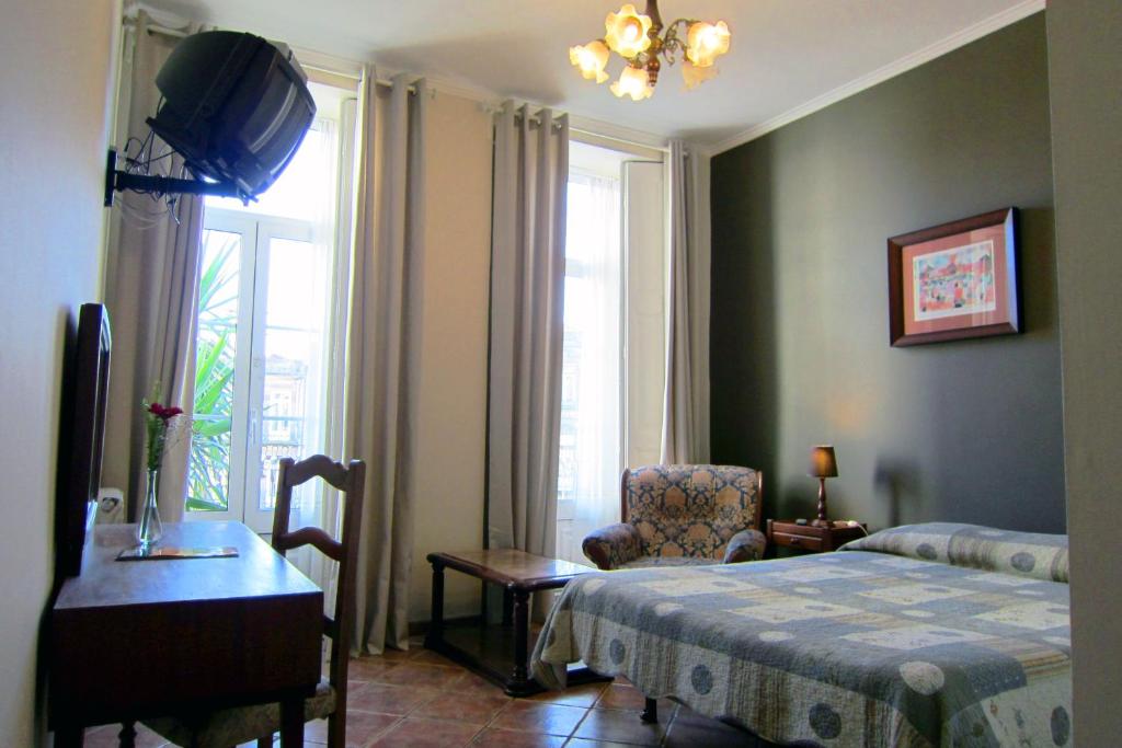 um quarto com uma cama, uma cadeira e uma janela em Duas Nações Guest House no Porto