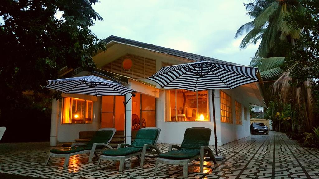 eine Terrasse mit Stühlen und Sonnenschirmen vor einem Haus in der Unterkunft White House, Batangas in Lian