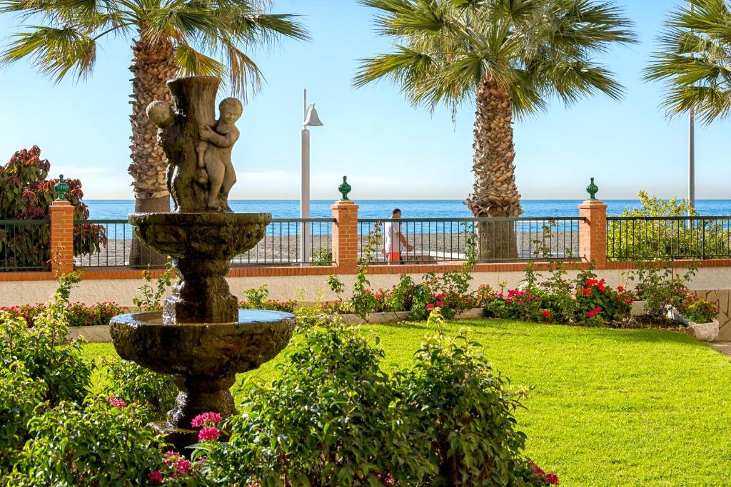 een fontein in een park met palmbomen en de oceaan bij WintowinRentals La Posada del Mar in Rincón de la Victoria