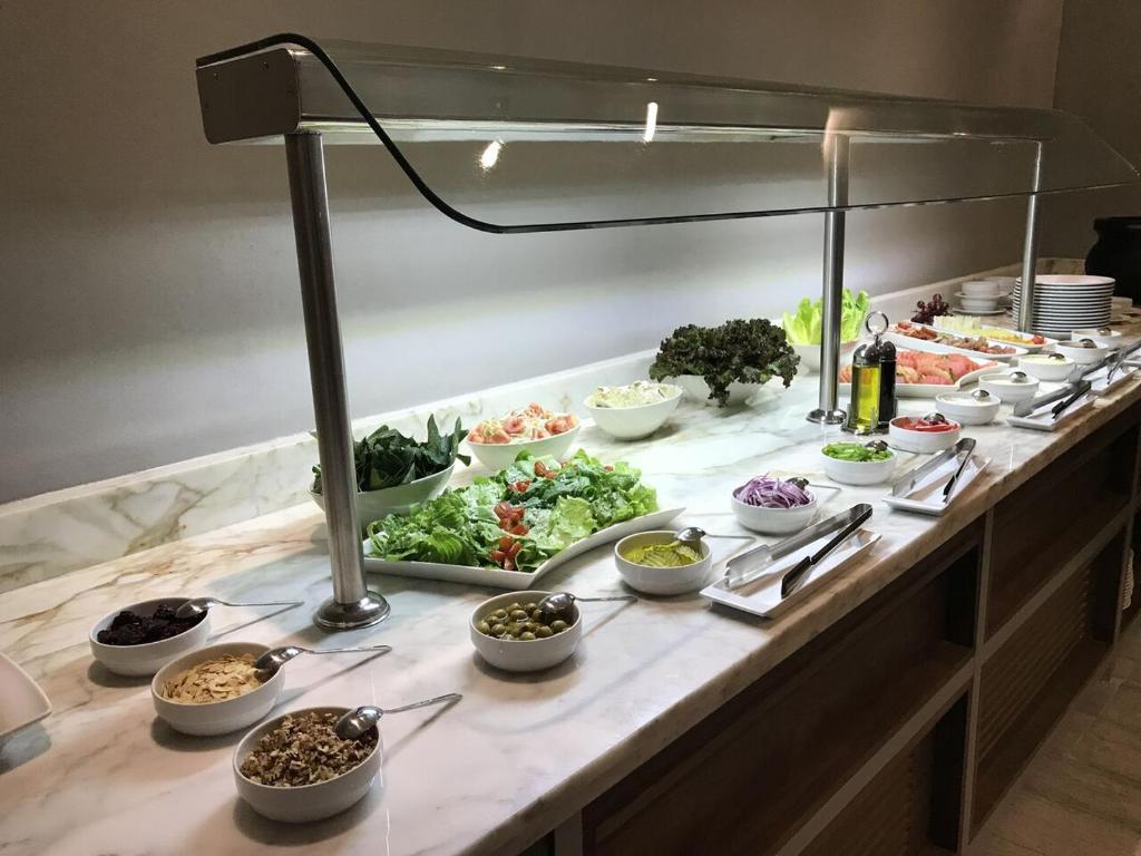 A refrigerated buffet counter offering salads, vegetables, toppings, fruit, and cereals.