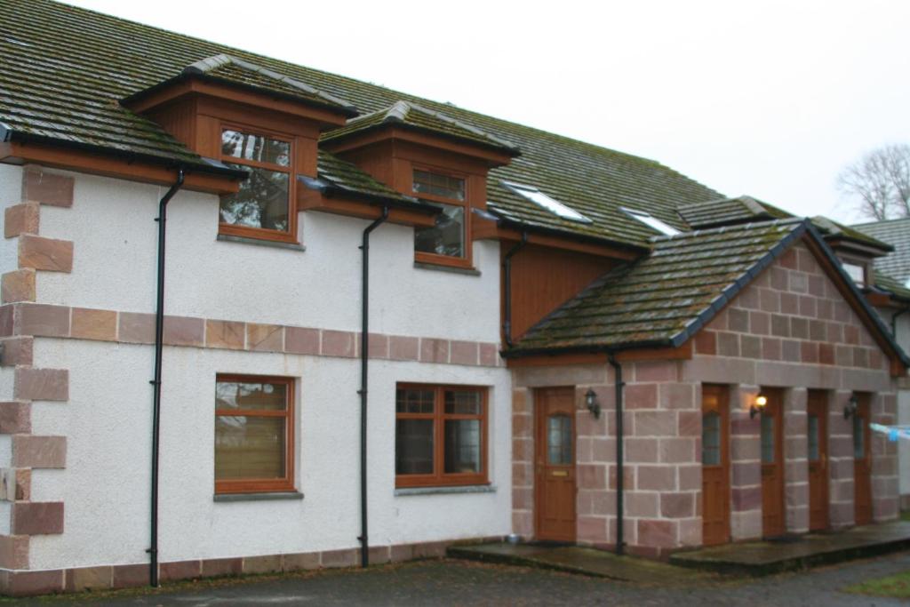 a house with a brown and white at Grey Stag Apartment in Nairn