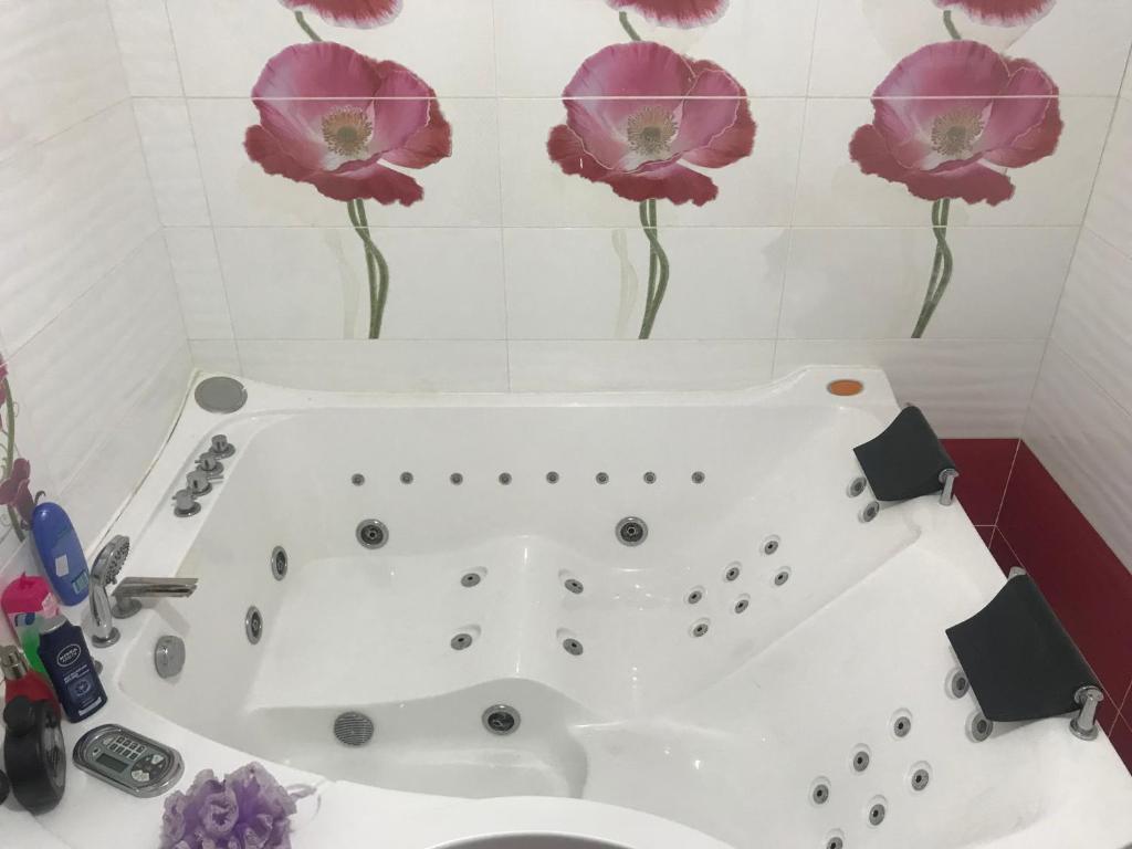 a bathroom with a bath tub with flowers on the wall at Coquelicot Tizi ouzou in Tizi Ouzou