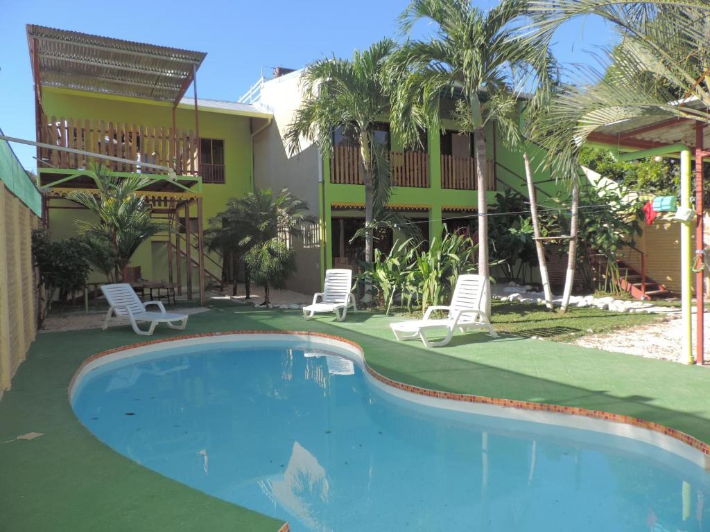 a pool in front of a house with two chairs and a building at chez philippe in Orotina