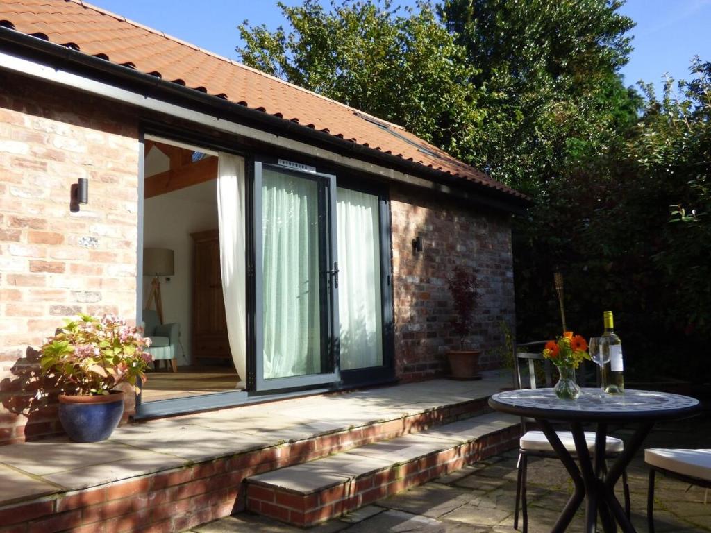 un patio con una mesa y una puerta de cristal en The Old Potting Shed, en York