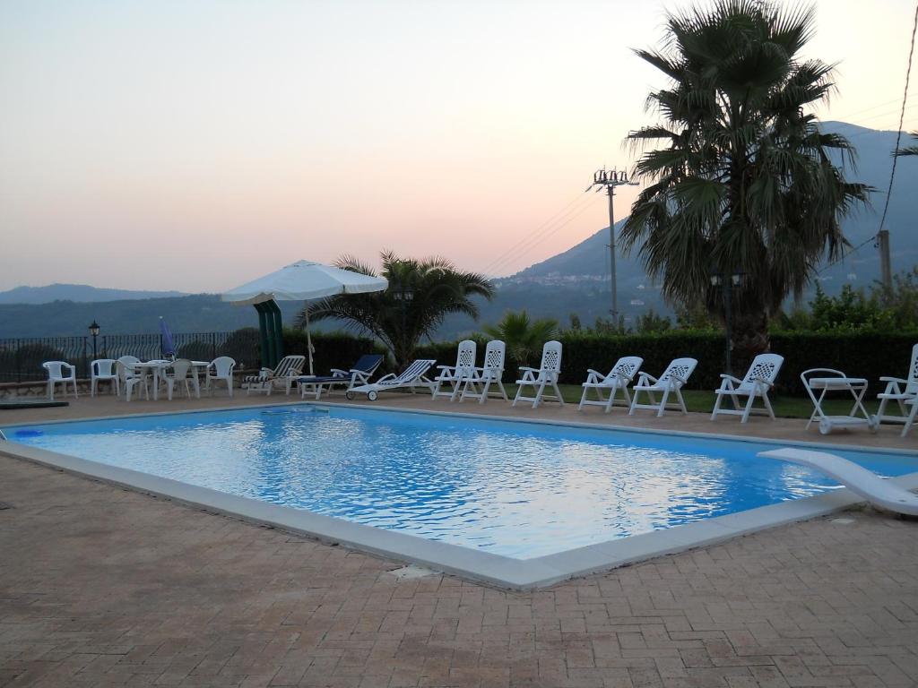 uma piscina com cadeiras e mesas e uma palmeira em Oasi Verde em Giffoni Sei Casali