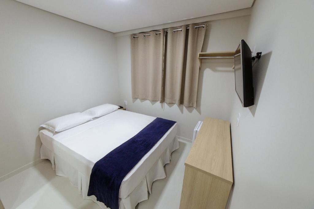 a small bedroom with a bed and a television at Ecotel in Ribeirão Preto