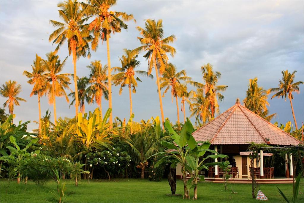 a resort with palm trees and a building at Bali Oase Resort in Pemuteran