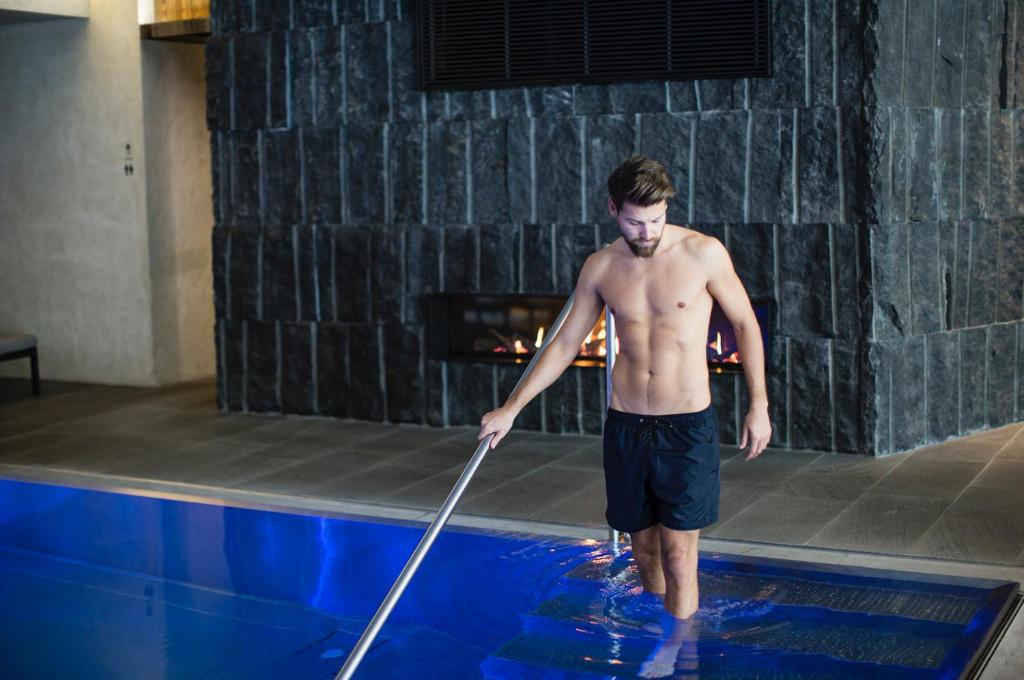 a shirtless man standing in a pool holding a bat at ElisabethHotel Premium Private Retreat- Adults only in Mayrhofen