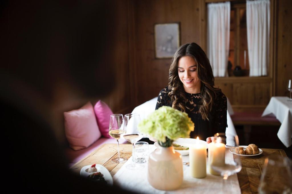 a woman sitting at a table with wine glasses at ElisabethHotel Premium Private Retreat- Adults only in Mayrhofen
