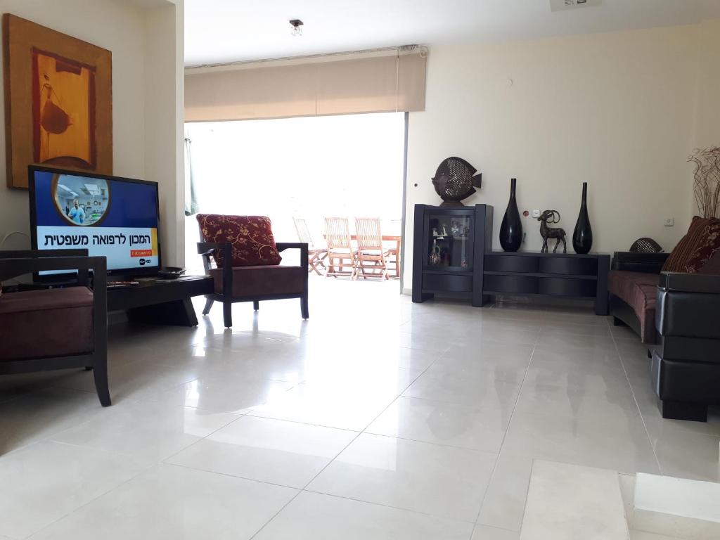 ein Wohnzimmer mit einem TV und Vasen an der Wand in der Unterkunft Exodus Marina Cottage Apartment Ashdod in Aschdod