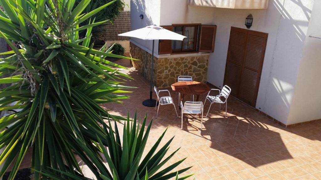 een patio met een tafel en stoelen en een parasol bij Casa Silencio in Corralejo