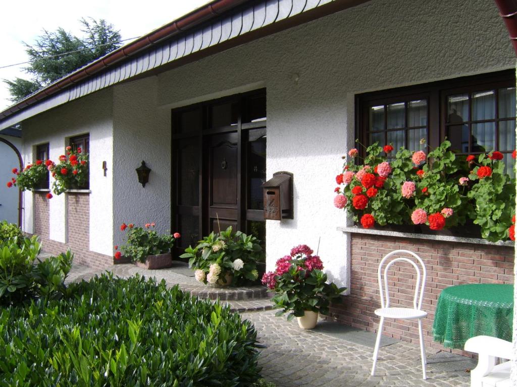 a white chair sitting outside of a house with flowers at Ferienwohnung "Am Fuchsgraben" in Tholey