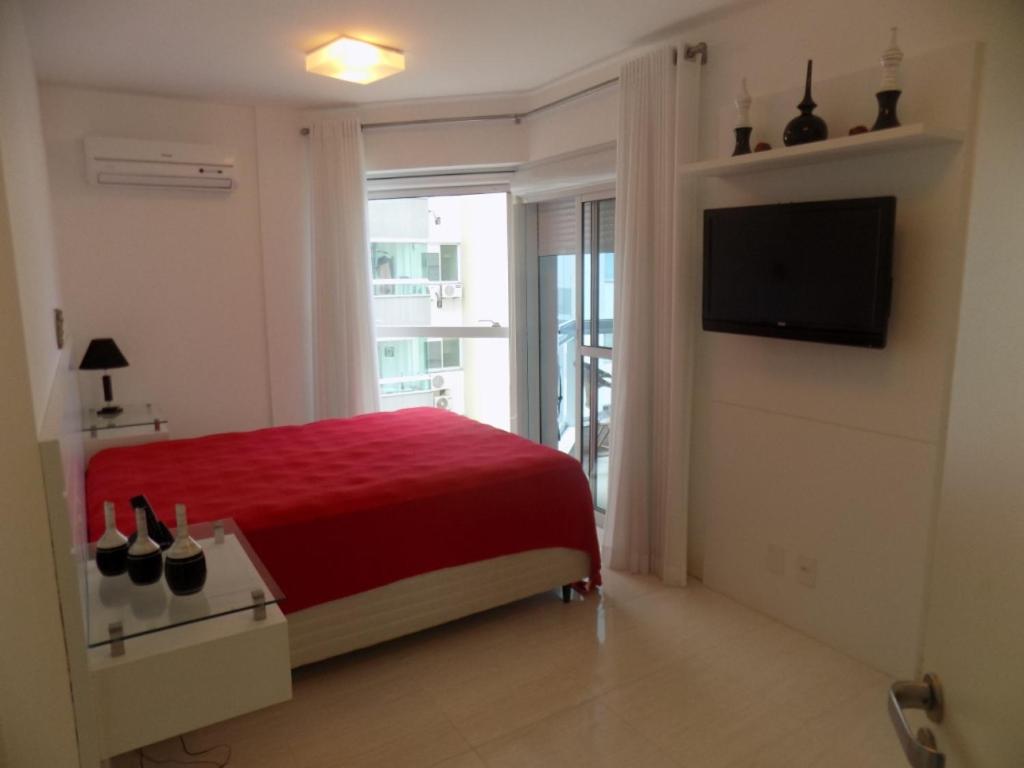 Schlafzimmer mit einem roten Bett und einem Flachbild-TV in der Unterkunft Temporada Praia de Palmas SC in Governador Celso Ramos