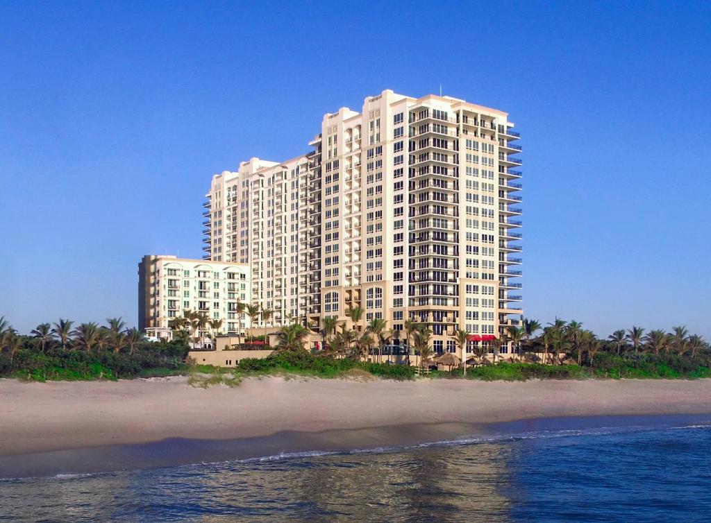 een groot wit gebouw aan het strand naast de oceaan bij Palm Beach Singer Island Resort & Spa Luxury Suites in Riviera Beach