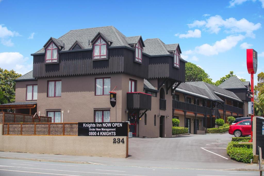 een groot huis met een bord ervoor bij Knights Inn in Auckland