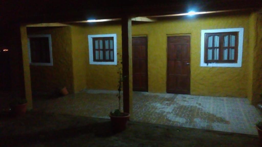 テルマス・デ・リオ・オンドにあるCabañas del Diqueの黄色の壁と夜間のドアが特徴の客室