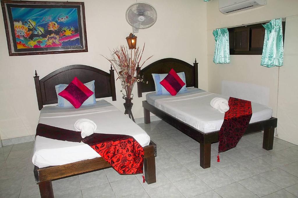 two beds in a room with red and white pillows at Seaworld Guesthouse in Ao Nang Beach