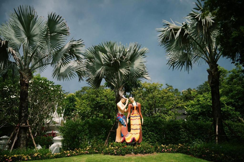 two women in dresses standing in front of palm trees at Doithinnan Resort in Nan
