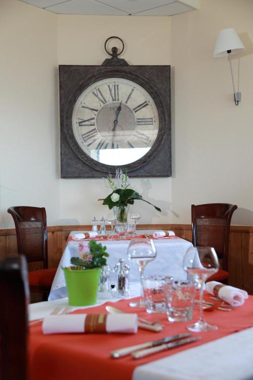 a table with a clock on the wall and a table with glasses at Hôtel Panorama in Munster