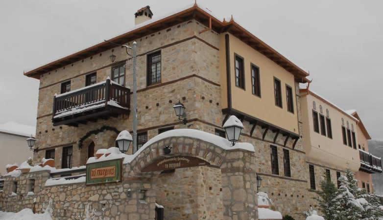 - un grand bâtiment en pierre avec de la neige dans l'établissement To Patriko, à Elatochori