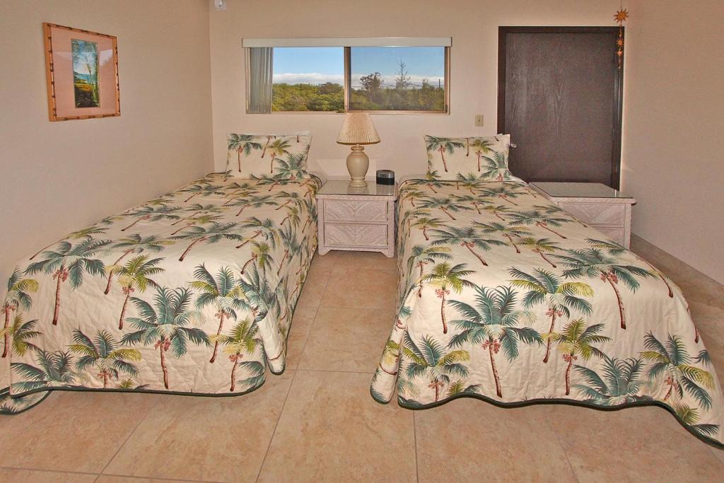 ein Schlafzimmer mit 2 Betten mit Palmen darauf in der Unterkunft Kihei Beach Resort 410 in Kihei