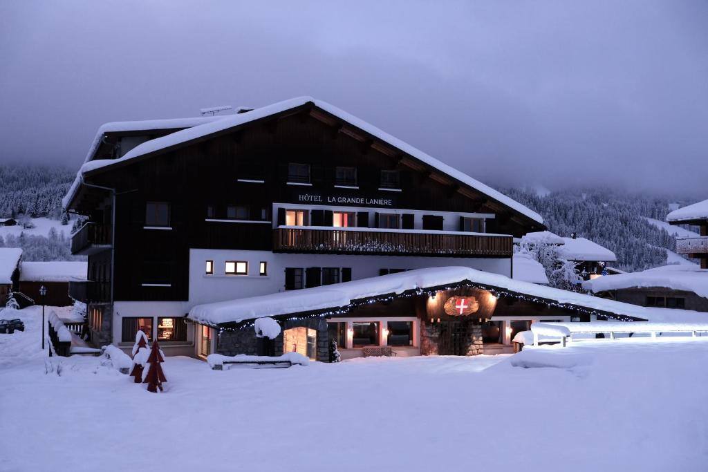 a large building in the snow with snow at Hôtel La Grande Lanière in Les Gets