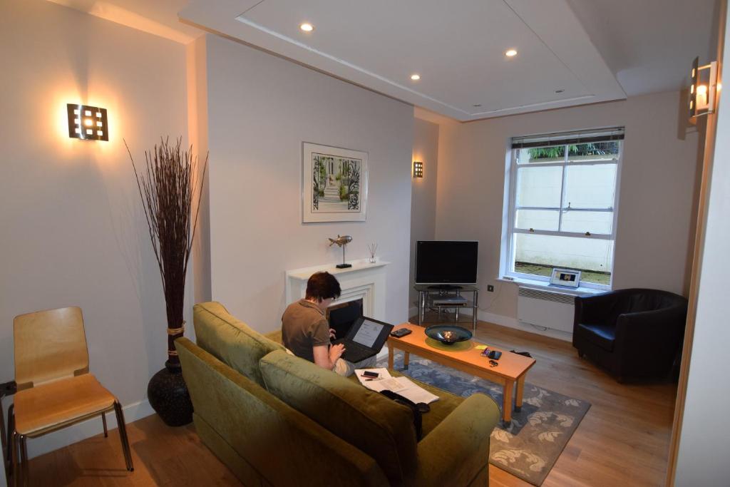 a man sitting on a couch using a laptop in a living room at Easby Hall 22 in Scarborough