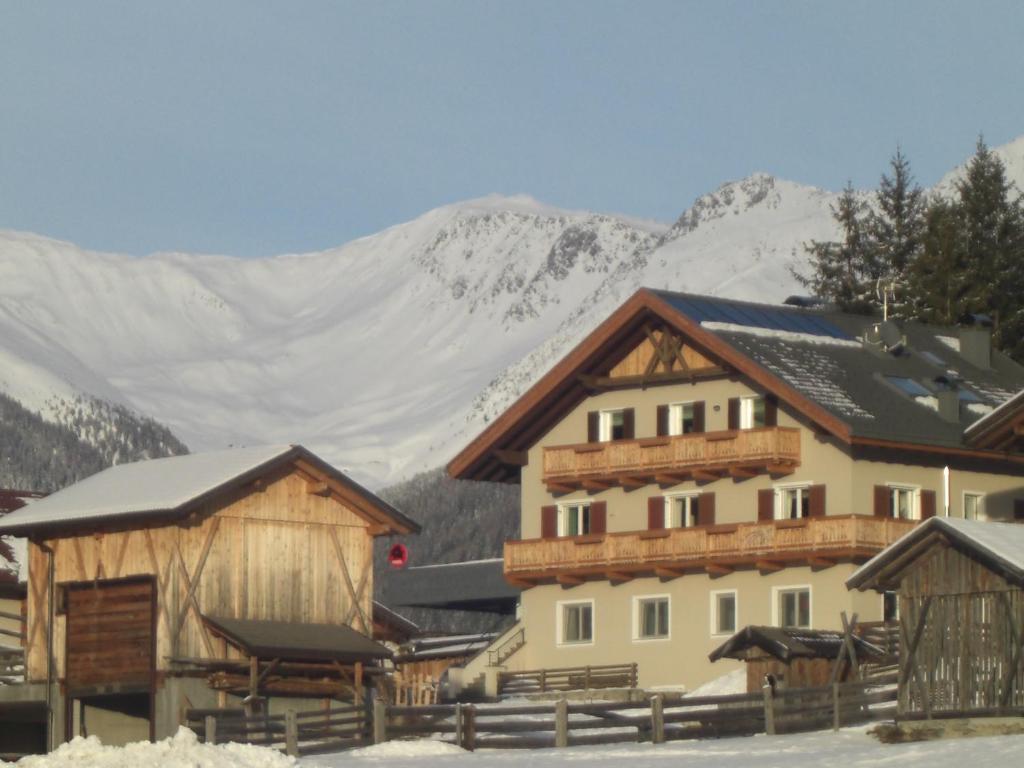 a group of buildings with snow covered mountains in the background at Haus Schaller in Valle Di Casies