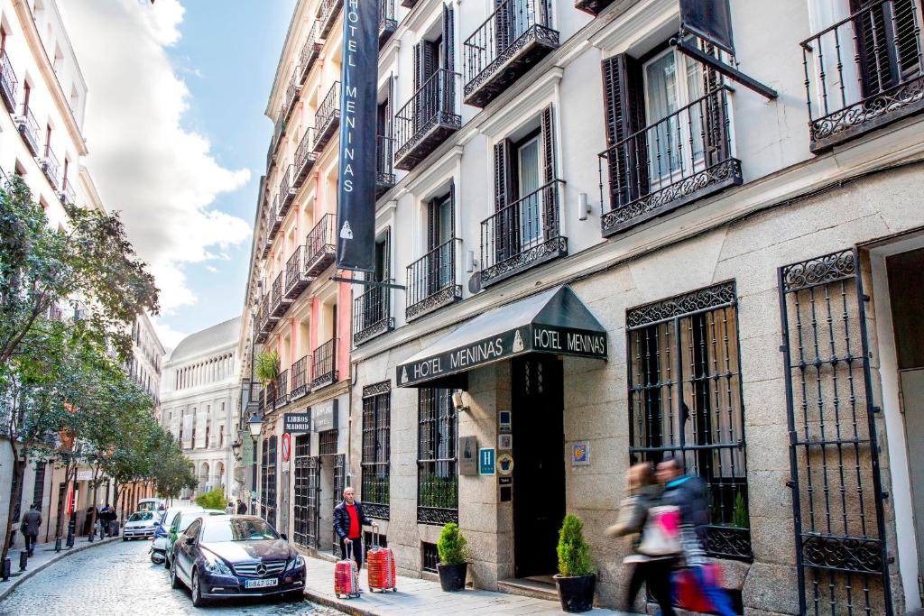 people walking down a street in front of a building at Hotel Meninas - Boutique Opera in Madrid