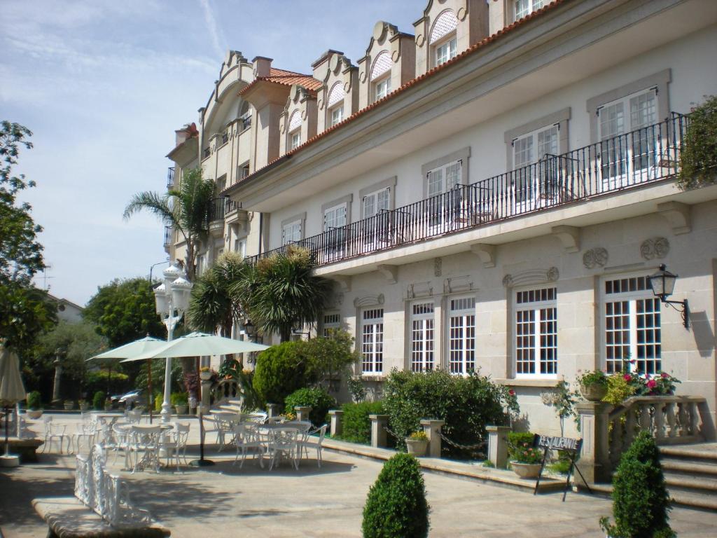a building with tables and chairs in front of it at Hotel - Restaurante Casa Rosita in Cambados