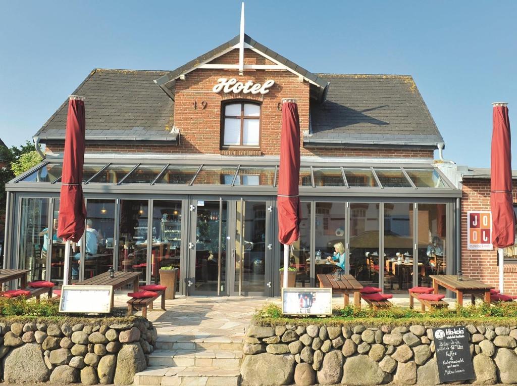 a restaurant with red umbrellas in front of a building at Hotel Kiose in Wenningstedt