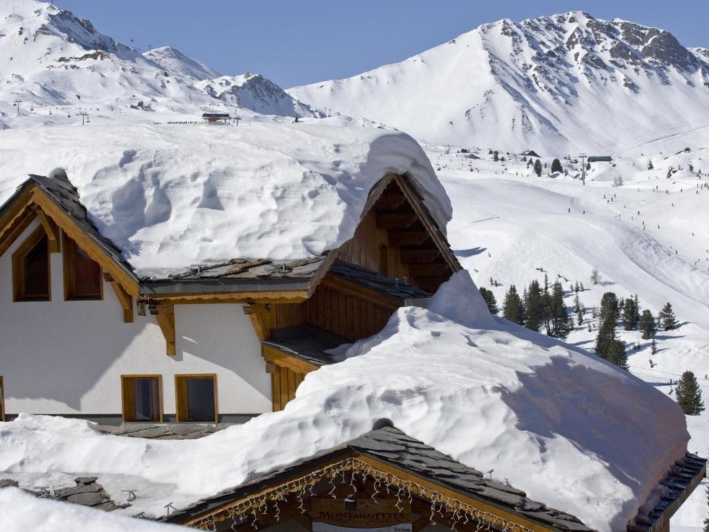 une maison recouverte de neige avec des montagnes en arrière-plan dans l'établissement Le Chalet du Vallon, à Belle Plagne