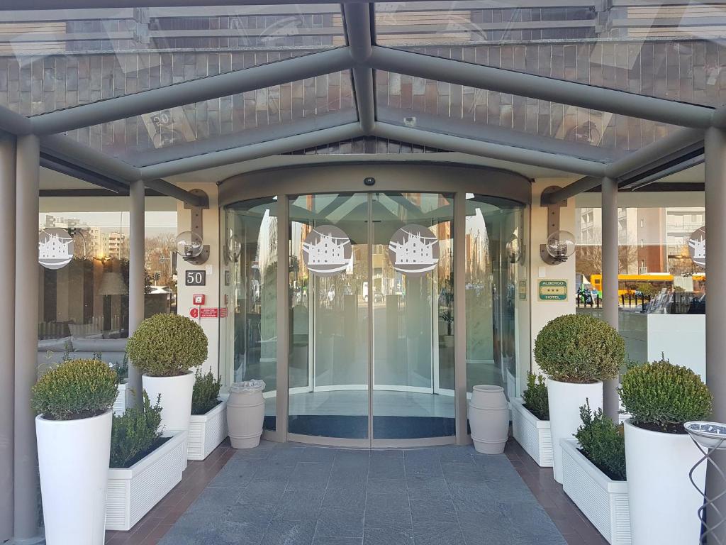 a glass entrance to a store with potted plants at Plus Welcome Milano in Milan